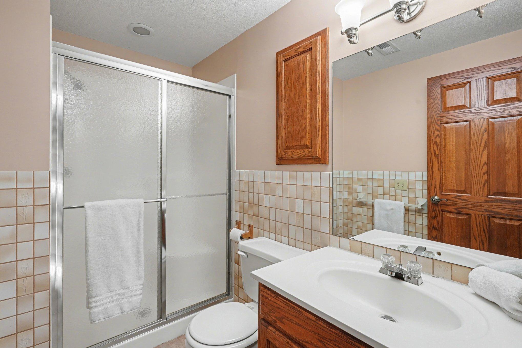 The lower-level 3/4 bath is designed for convenience! Features a shower, vanity with storage, and a built-in medicine cabinet. Perfect for guests or family! Just outside the bath is a large coat closet.