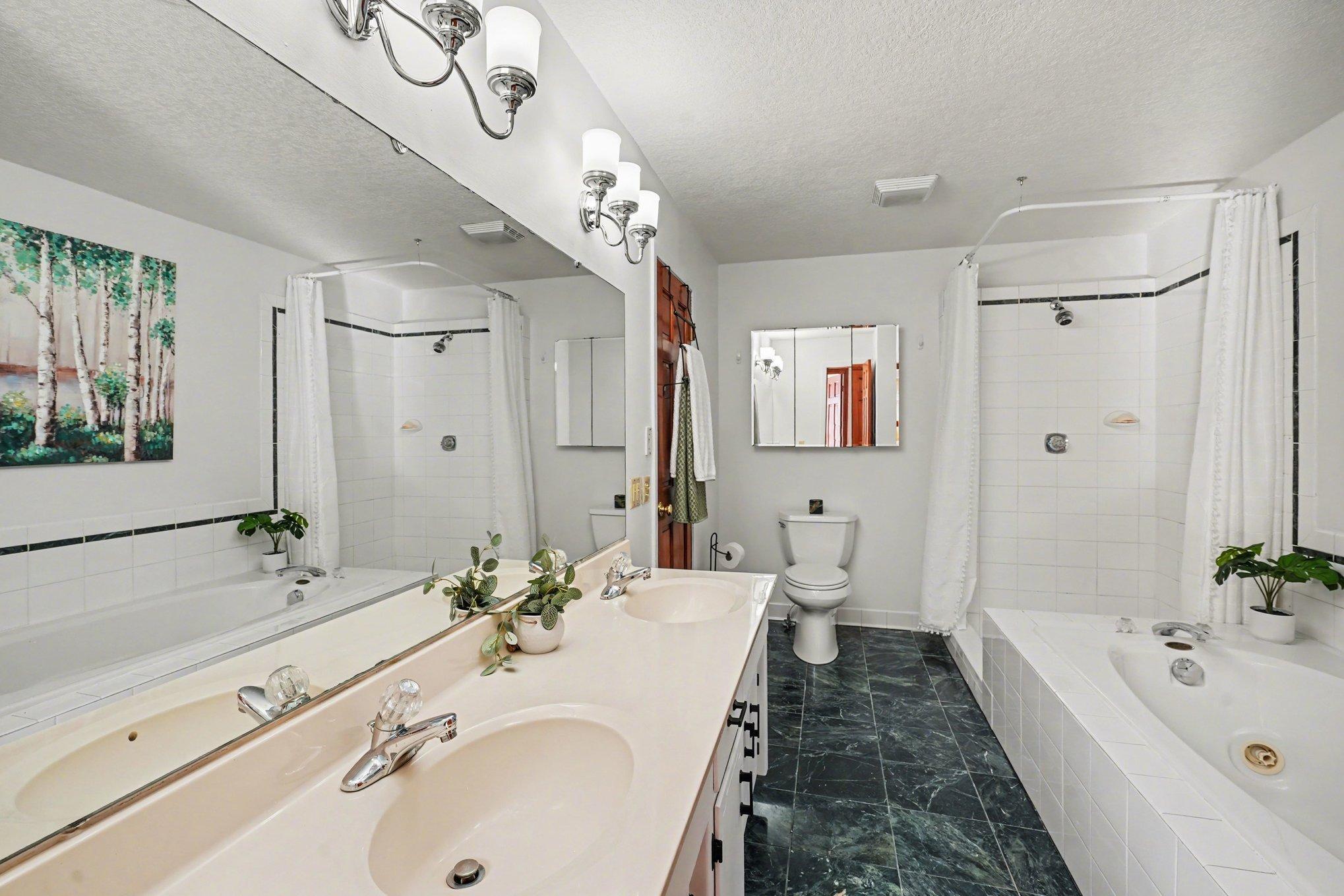 The upper-level passthrough bath is a true retreat! Features a dual sink vanity, ceramic tile floors, a separate shower, and a deep jetted tub. Luxury and convenience in one beautiful space!