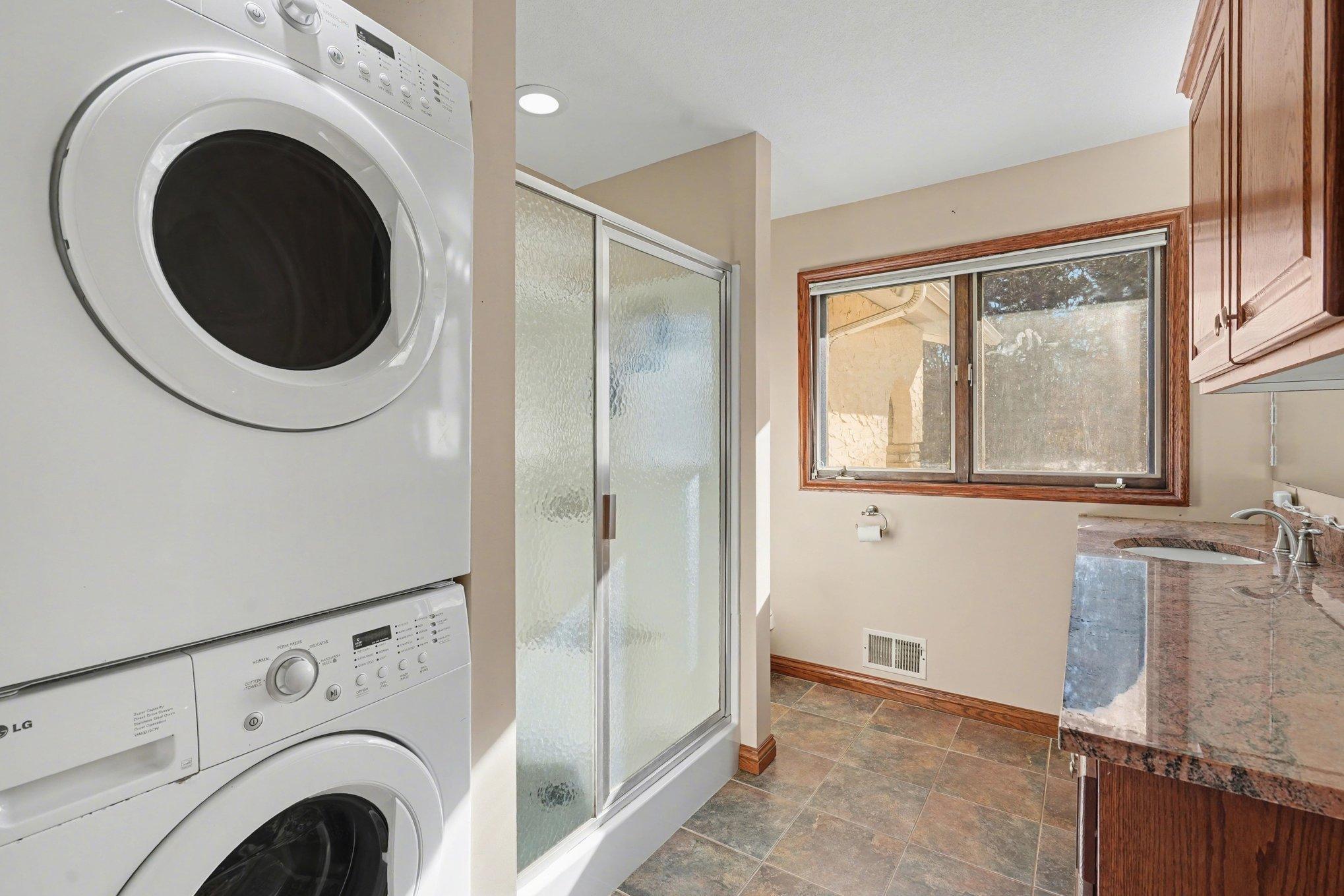 Natural light fills this upper-level laundry and bath! Includes a stackable washer/dryer set and a large window offering lovely wooded views. Making laundry day a scenic retreat!