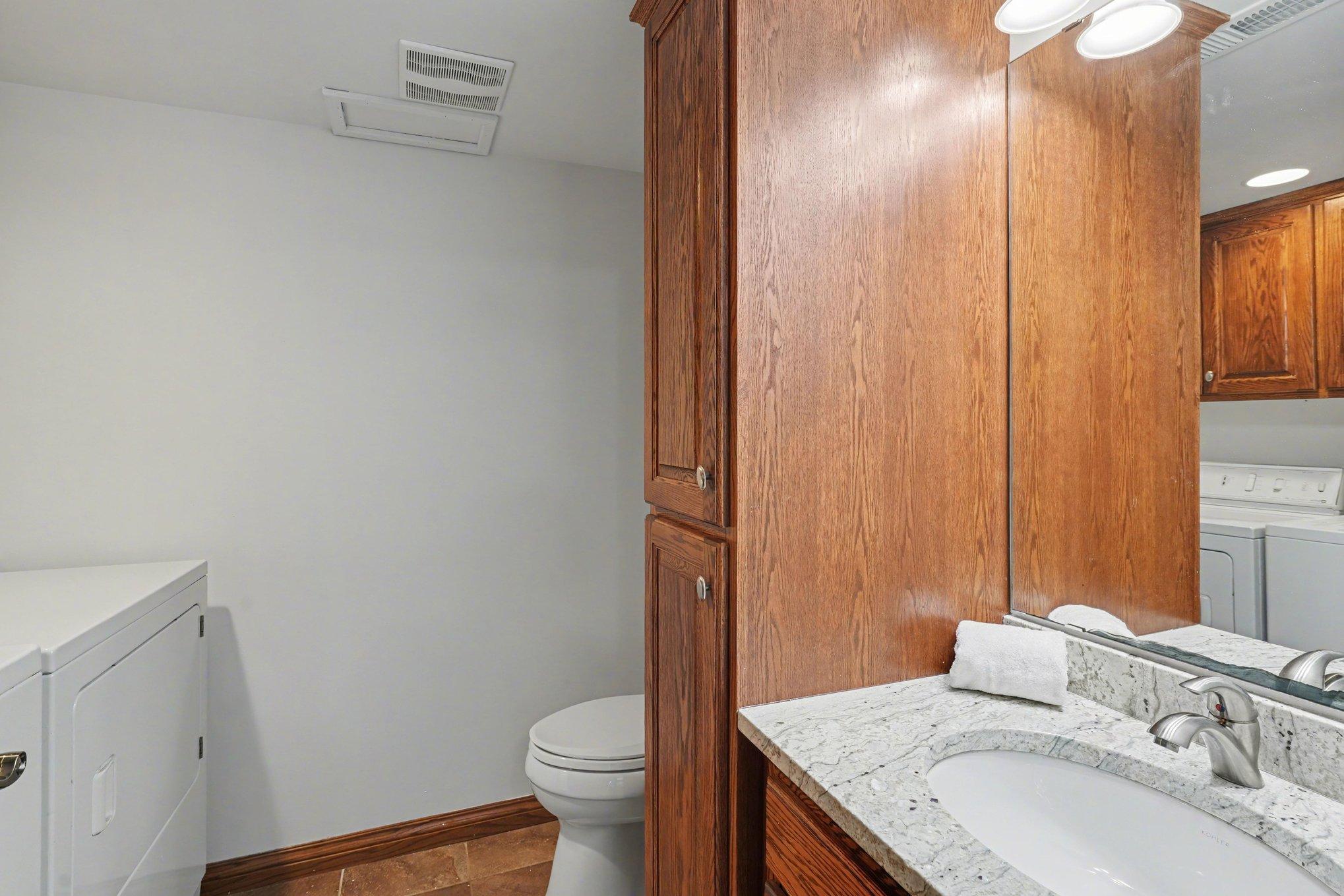The half bath features washer/dryer hook-ups, granite counters, & ceramic tile. With abundant cabinetry for all your storage needs, this lower-level space adds incredible convenience to the home!