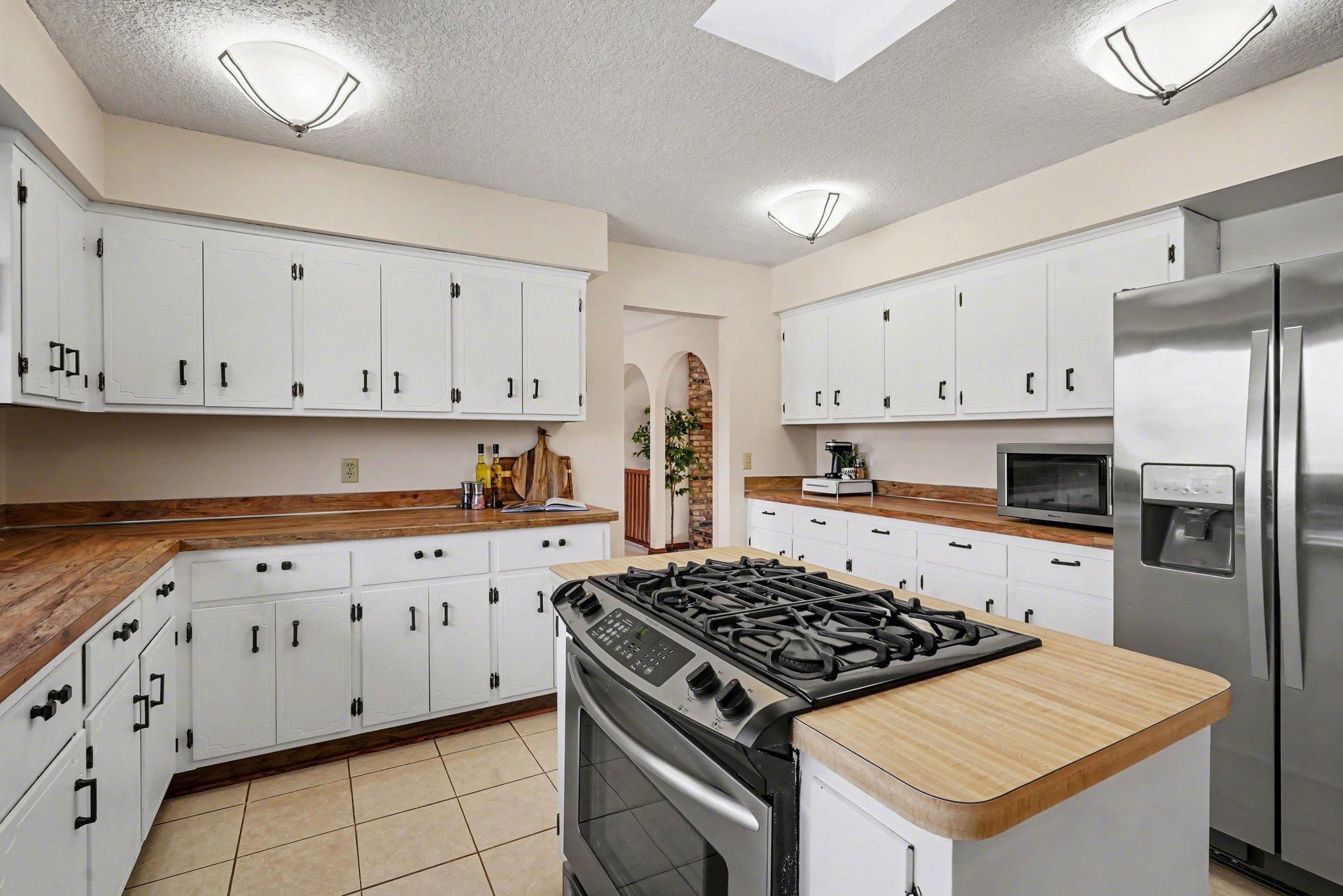 This view highlights the endless storage and prep space. The kitchen features beautiful ceramic tile floors and an added skylight that keeps the kitchen bright and airy all day.