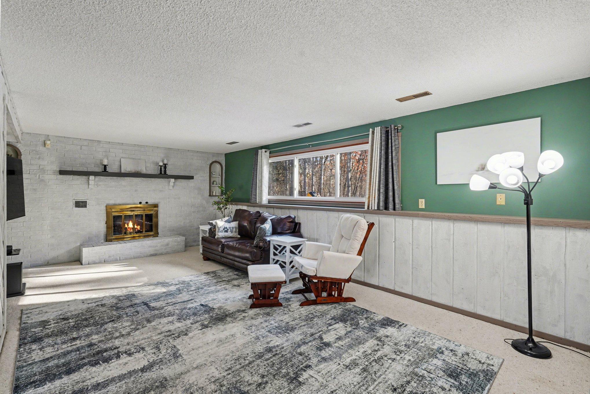 Enjoy movie night by the fire! This spacious lower-level family room includes a classic brick wood-burning fireplace and lookout windows that keep the space bright.