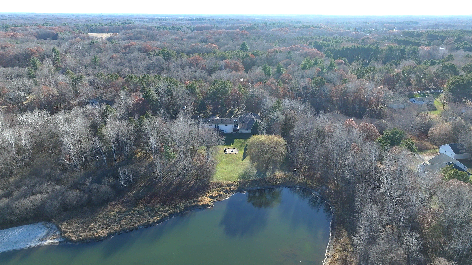 Aerial view of the gorgeous wooded lot and the pond. Your private oasis awaits!