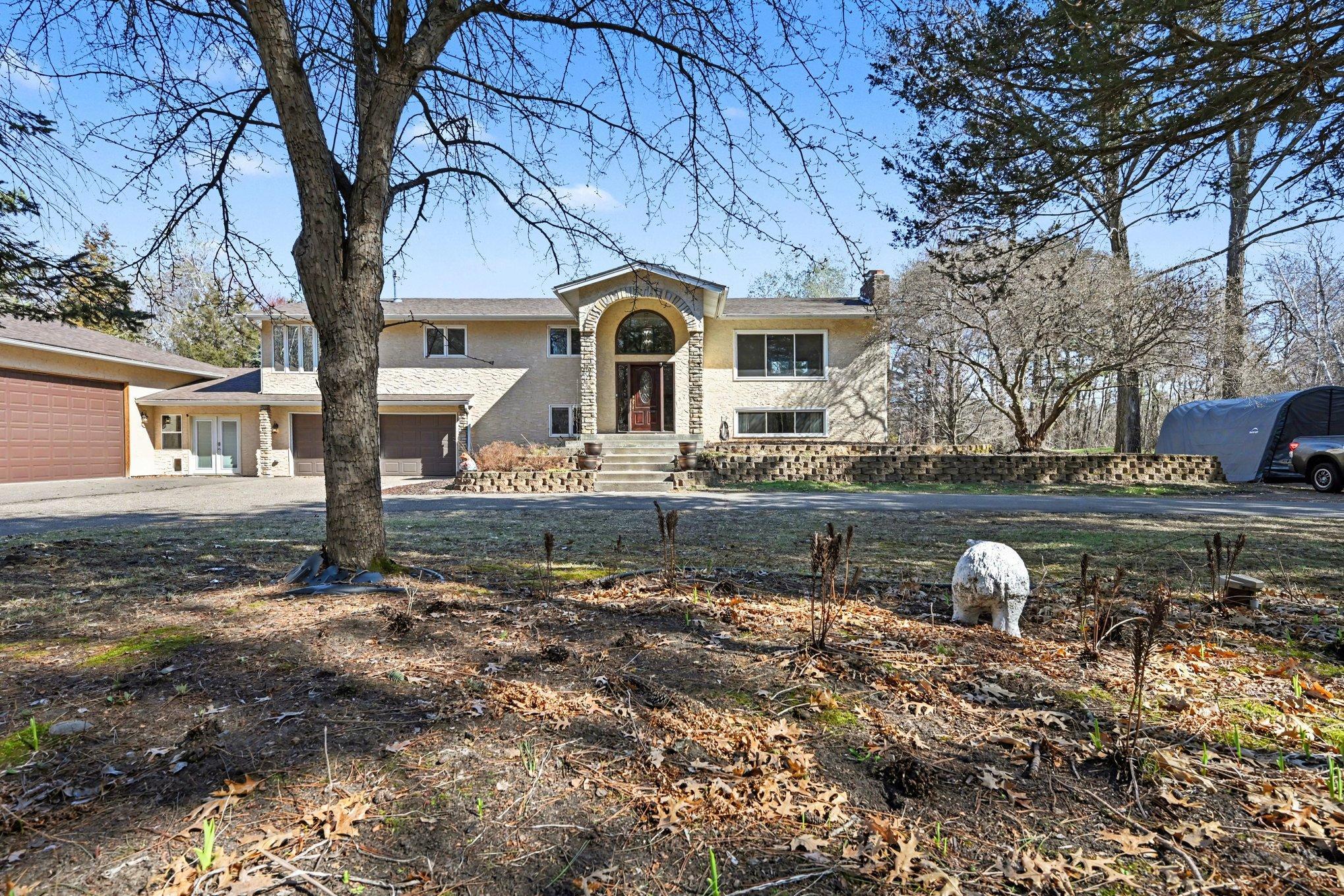 Front view of the property highlighting the generous driveway. This space offers ample guest parking and versatile storage options for vehicles, boats, or recreational equipment. Beautiful perennial gardens around the front of the home.