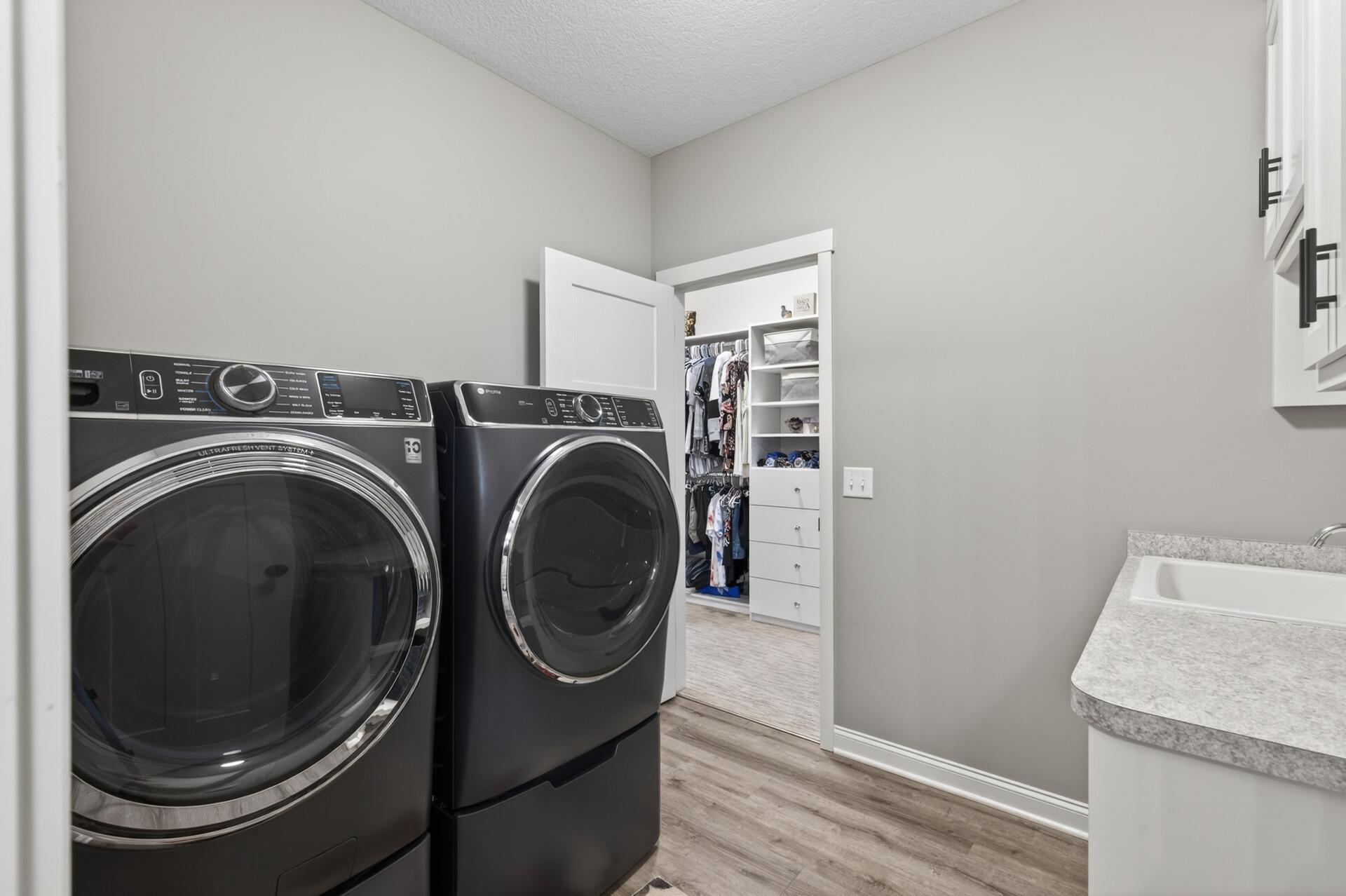 Main level laundry room that connects to the primary bedroom walk-in closet