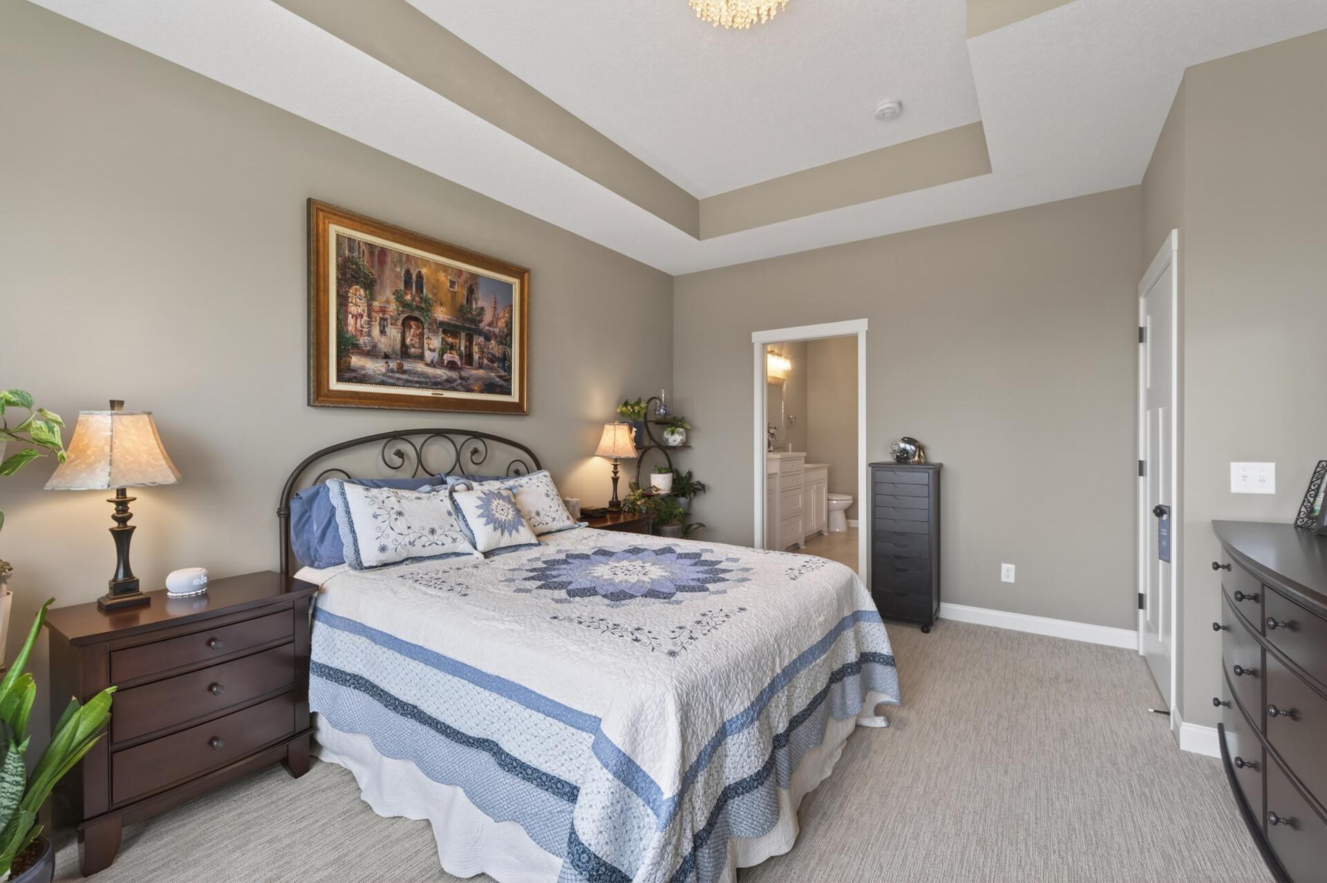 Primary bedroom with tray ceiling and windows that bring in tons of light!
