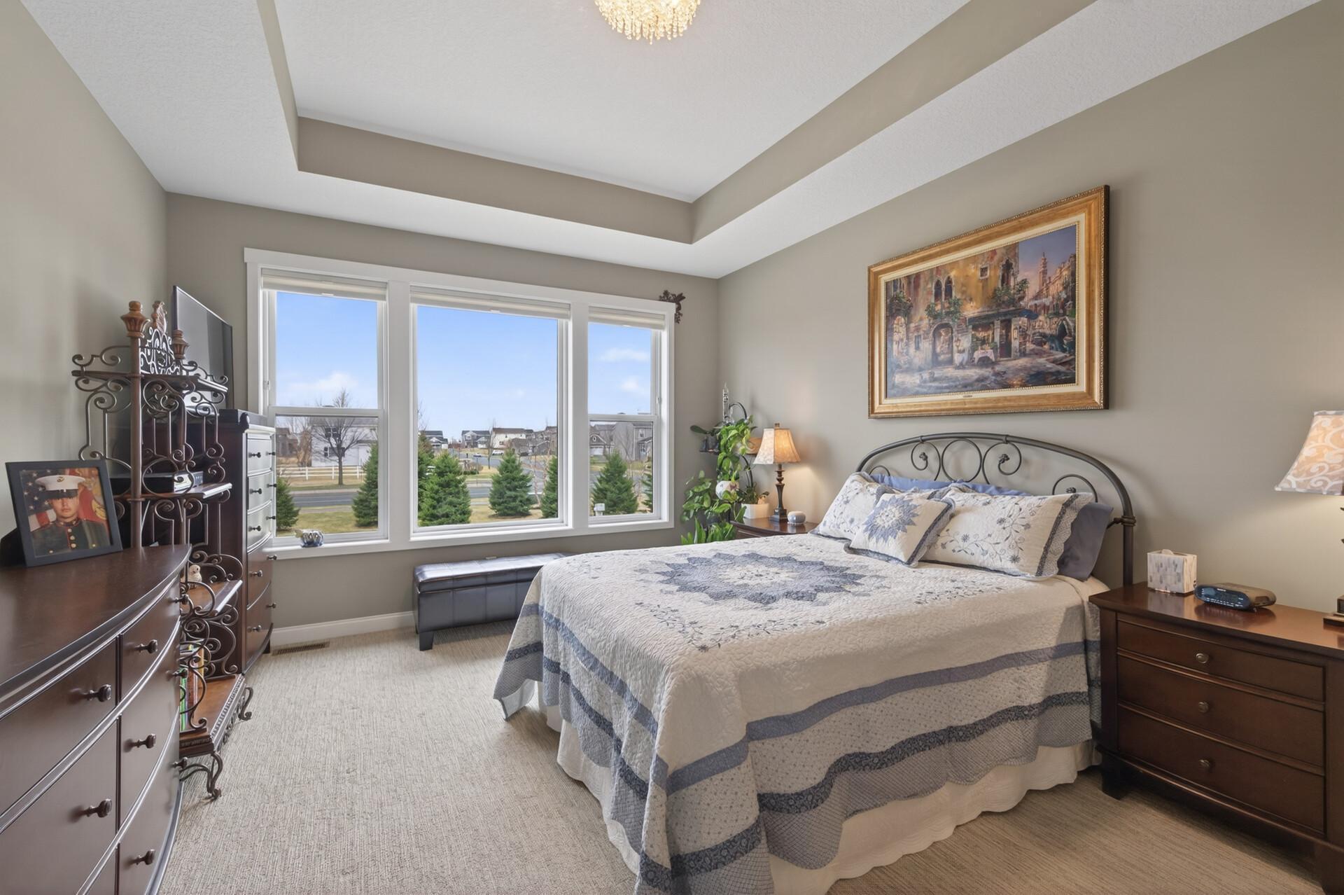 Primary bedroom with tray ceiling and windows that bring in tons of light!
