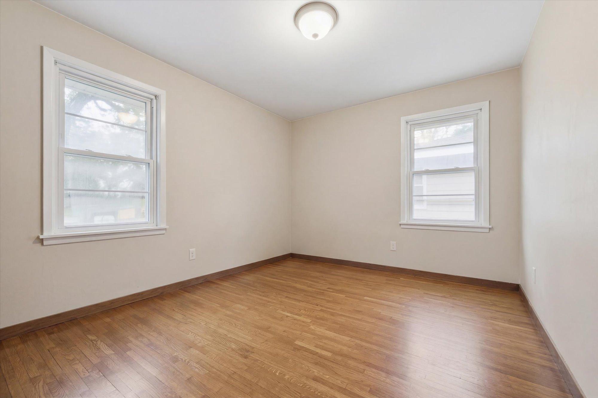 Comfortable second main-level bedroom offering hardwood floors, multiple windows for natural light, and a walk-in closet for added storage.