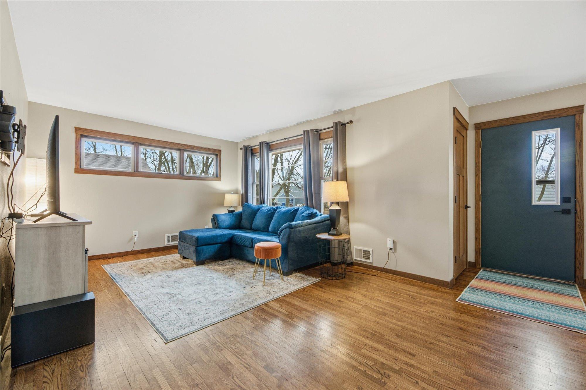 Warm and welcoming living space filled with natural light, showcasing hardwood floors and a cozy layout ideal for relaxing or entertaining.