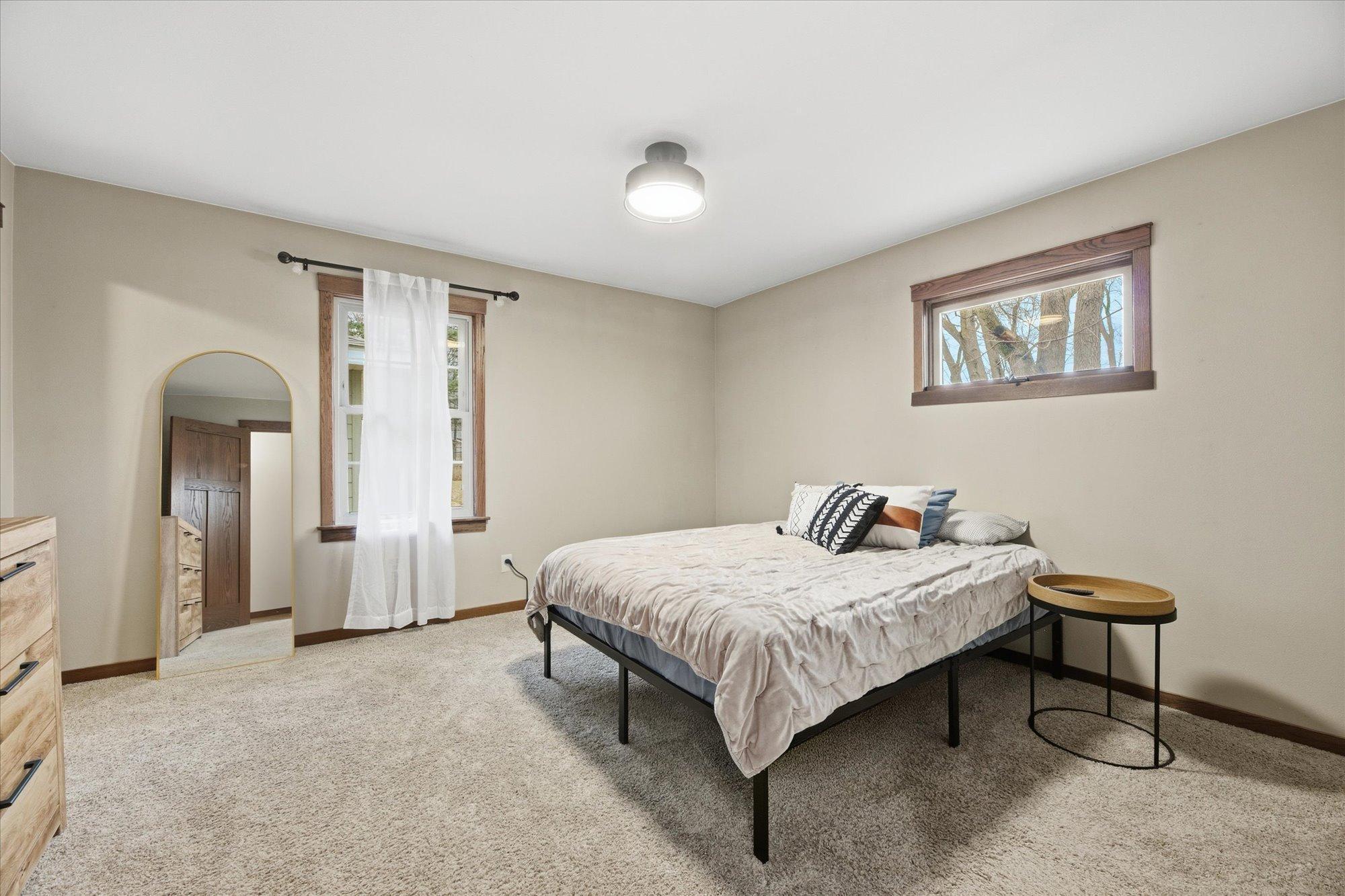 Generous main bedroom offering soft carpeting, neutral finishes, and multiple windows for natural light.