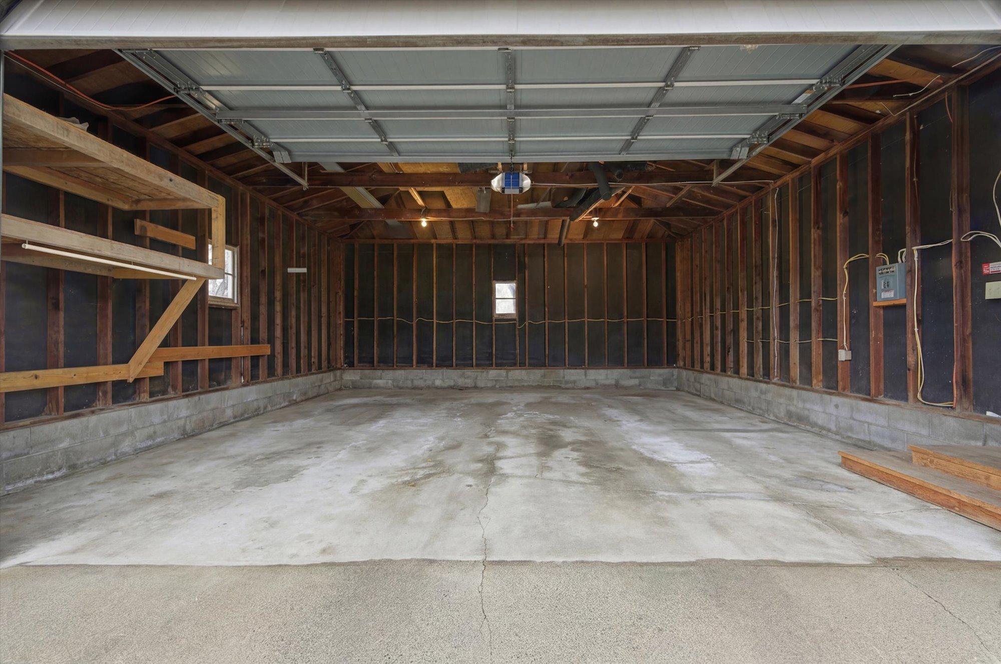 Oversized two-car garage with high ceilings, virtually decluttered to illustrate the ample space for parking, storage, or a workshop setup.