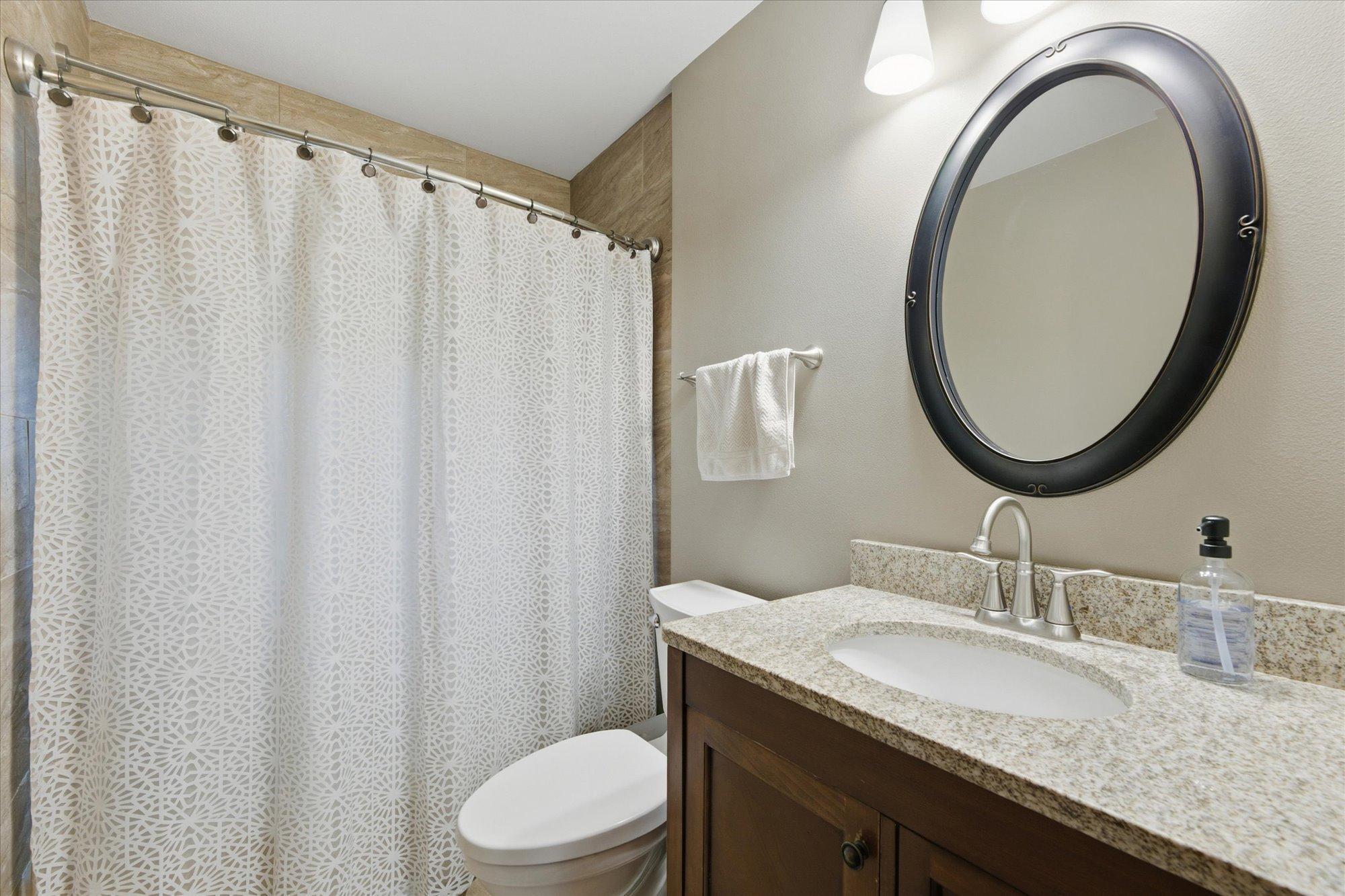 Stylishly updated main floor bathroom with granite vanity top and beautifully tiled tub/shower surround.