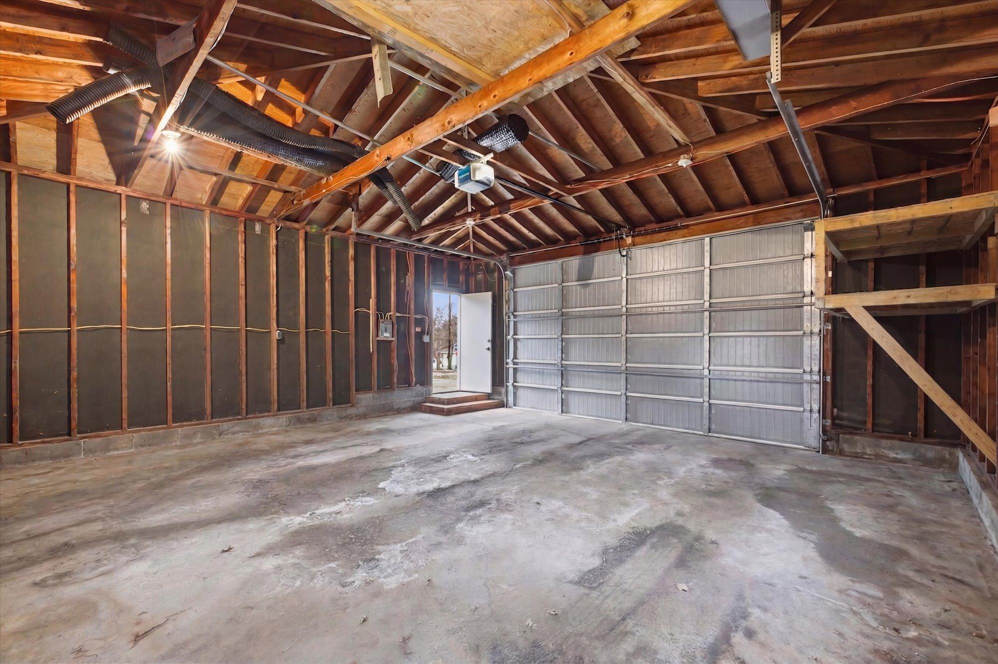 Oversized two-car garage with high ceilings, virtually decluttered to illustrate the ample space for parking, storage, or a workshop setup.