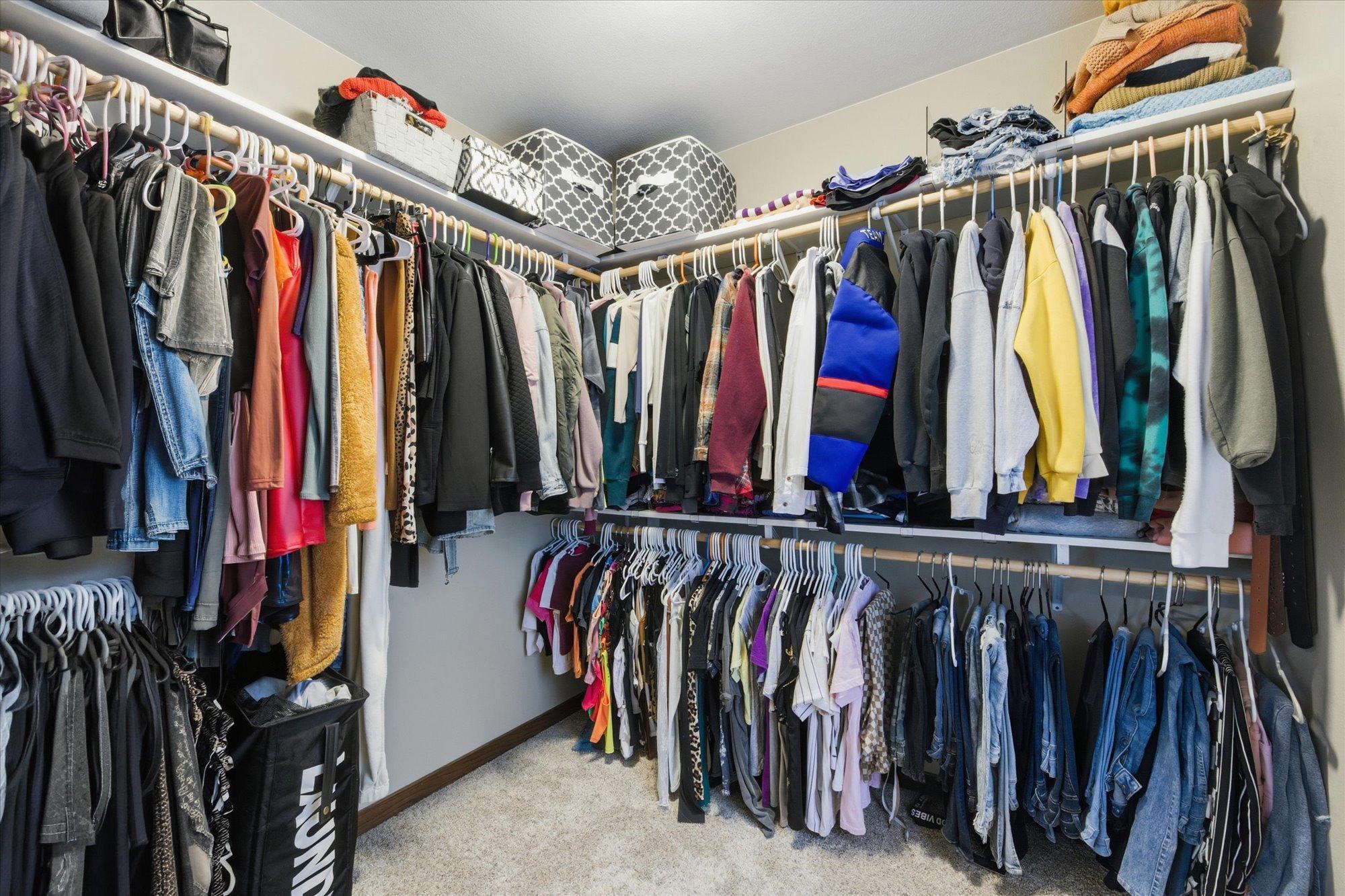 Generous walk-in closet with dual hanging rods and upper shelving, offering excellent organization and storage.