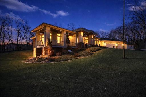 A stunning twilight view of this custom-built home, illuminated to highlight its architectural detail and private setting.