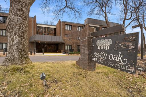 Welcoming exterior with circular drive and mature trees, offering a private, park-like setting at Seven Oaks Condominiums.