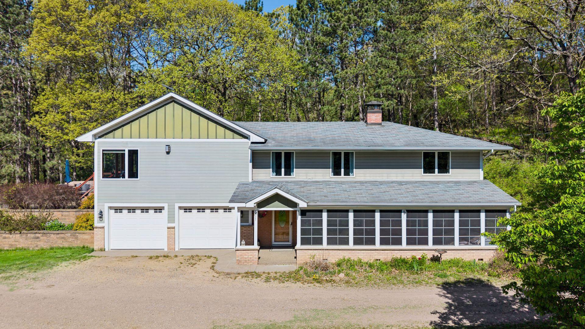 A welcoming front exterior with a 2-car tuck-under garage and a spacious screen porch to enjoy quiet, bug-free evenings.