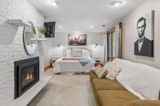 A spacious primary suite with serene views, direct access to the screen porch, and a newly upgraded gas fireplace.