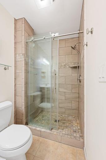 Retreat to your updated primary bath showcasing custom tile work for a high-end, spa-like feel.
