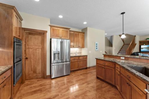 The kitchen features a large island, granite countertops, stainless steel appliances, custom cabinets and a large pantry.