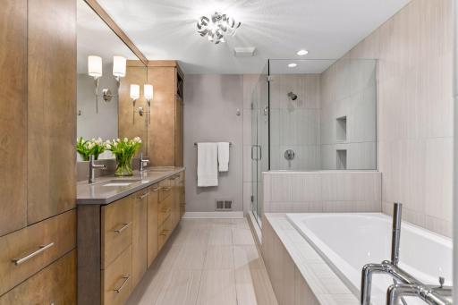 The primary bath with a glass enclosed shower, soaking tub, dual sinks and tons of storage