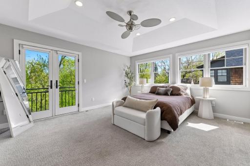 The spacious primary bedroom flooded with natural light from the large windows and a charming "juliet" balcony
