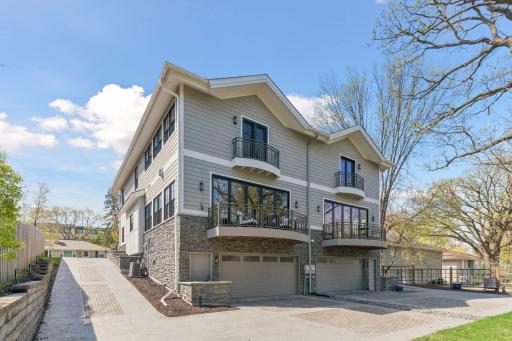 A view of the two car garage and concrete driveway finished with upgraded pavers and stone