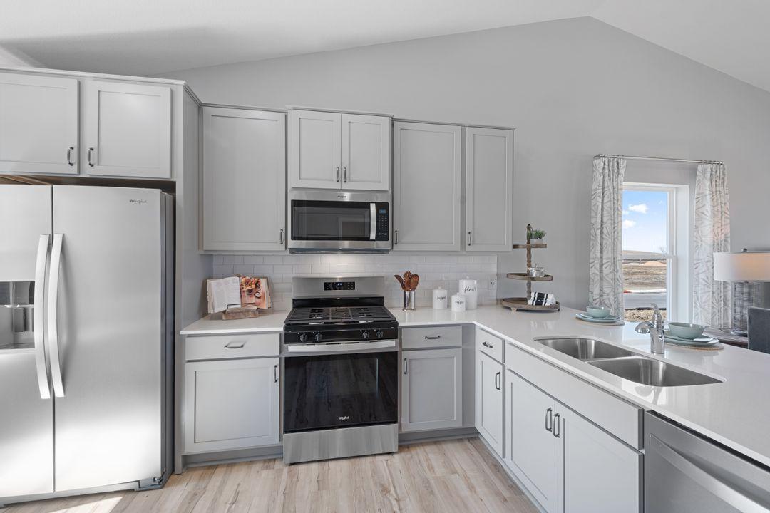 Kitchen shown with Willow gray cabinets, gas oven/range, microwave over cooktop, and quartz countertops. Photos is of model home. Colors and options may vary. Ask Sales Agent for details.