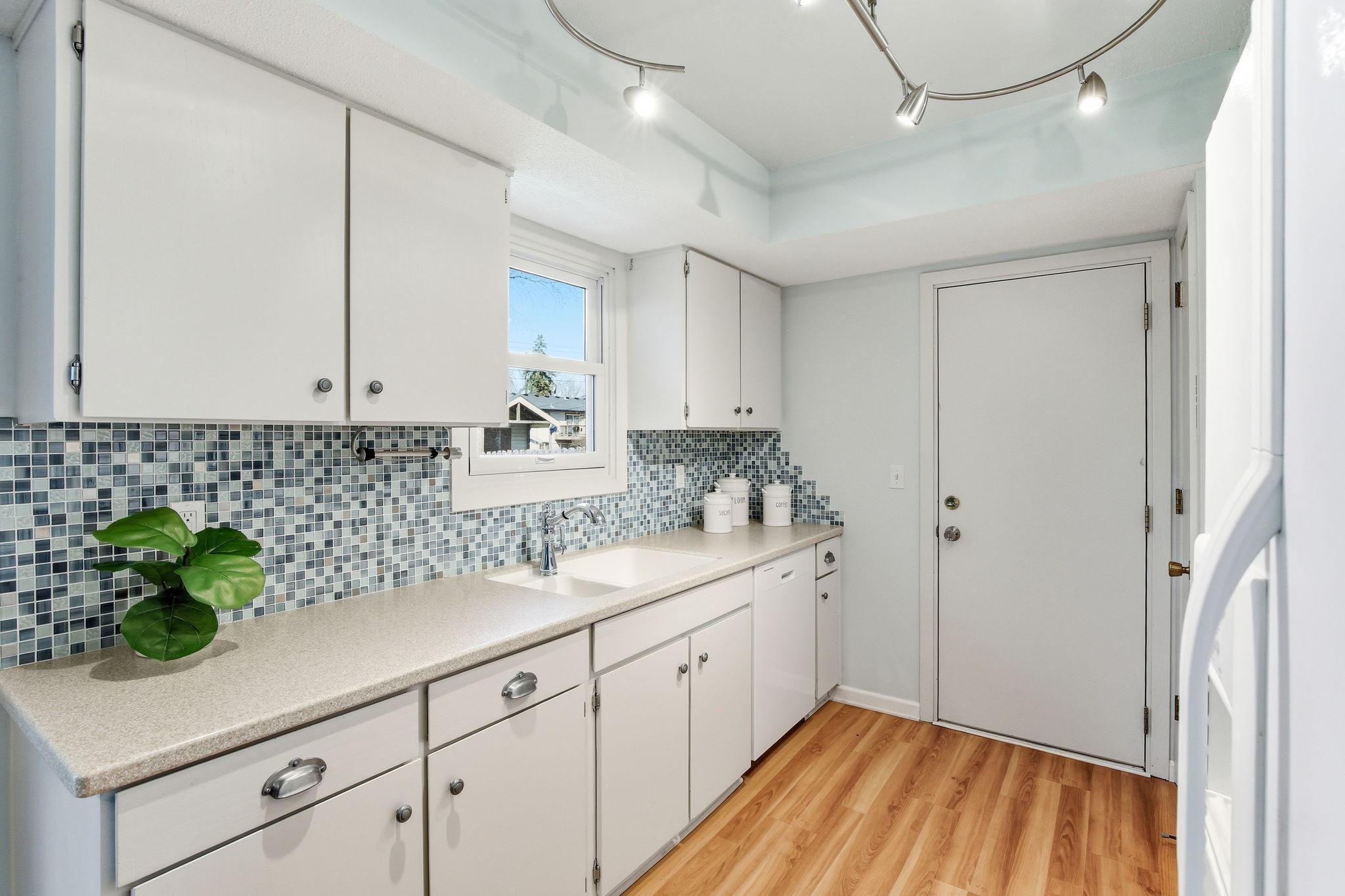 White Cabinets with Kitchen Window to the Backyard.