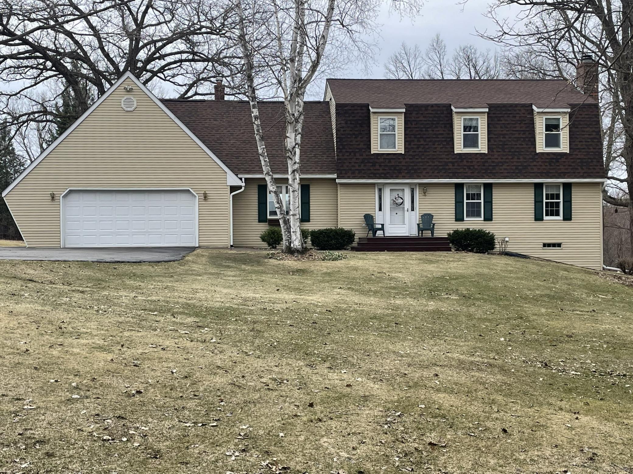 Two-story home surrounded by mature trees and open land