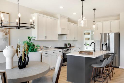 This home is enhanced by stunning designer lighting, the elegant pendant lights over the kitchen island & a beautiful chandelier in the dining room. Photos are from previously built home; options and features may vary.