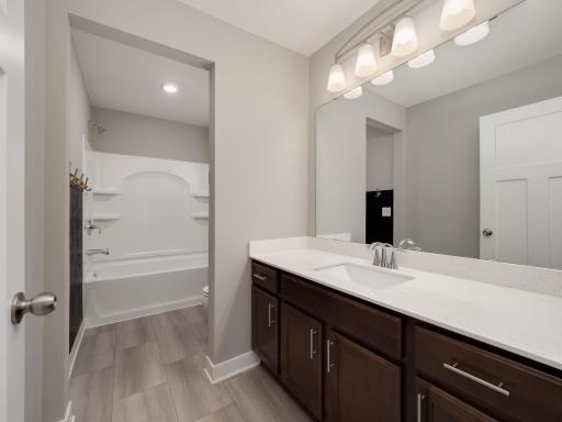 Upper level full bath between the laundry room and the owner suite serves the bedrooms on the upper floor.