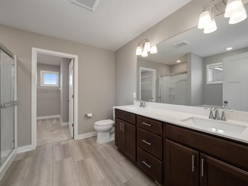 Owner's private bathroom has double basin sinks lots of cabinetry, large mirror, and great lighting. The owners closet is in the background.