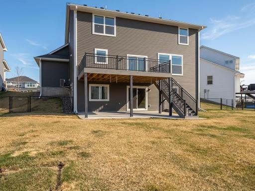 Rear view of the home showing the deck and lower concrete patio. There are gates both to the left and the right leading to the front yard.