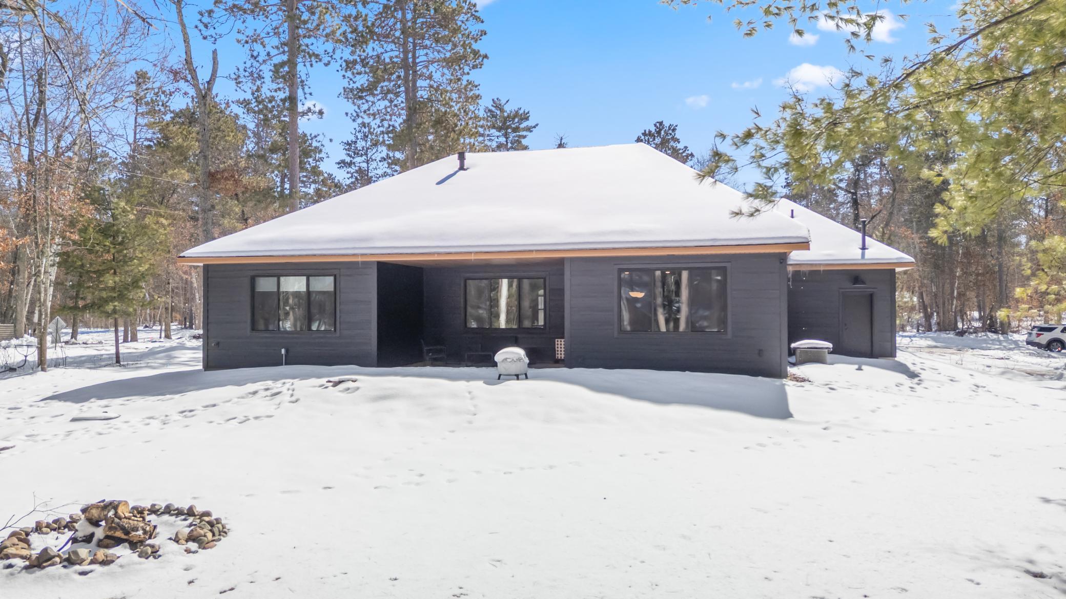From the backyard, the home’s sleek, modern design is beautifully complemented by the surrounding mature tree coverage.