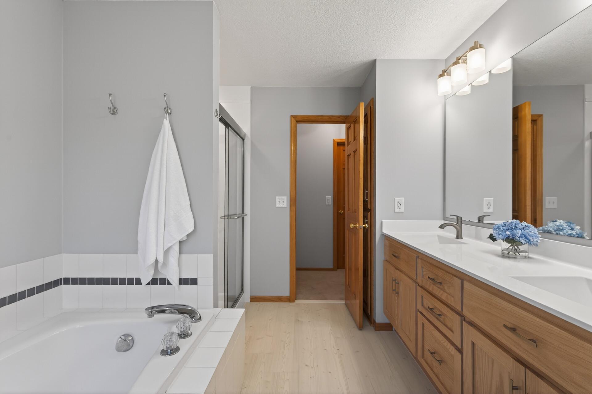 Primary full bath with dual sink vanity, soaking tub & new shower & flooring. Across the hall is the large walk-in closet