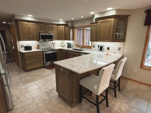 Remodeled kitchen with stone countertops, refinished custom cabinetry, and updated appliances.