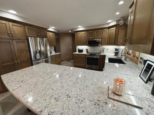 Remodeled kitchen with stone countertops, refinished custom cabinetry, and updated appliances.