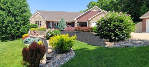 Summer views of the beautifully landscaped yard with thoughtfully designed retaining walls creating visual interest and functional outdoor spaces.