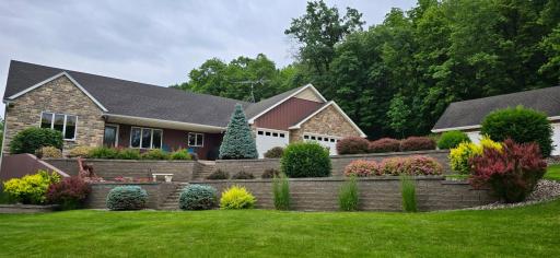 Summer views of the beautifully landscaped yard with thoughtfully designed retaining walls creating visual interest and functional outdoor spaces.