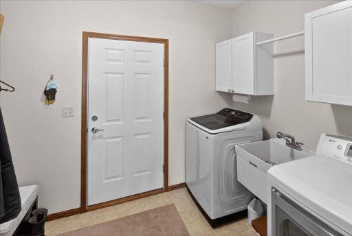 Convenient main-level laundry room with utility sink, storage cabinets, and extra space for organization.