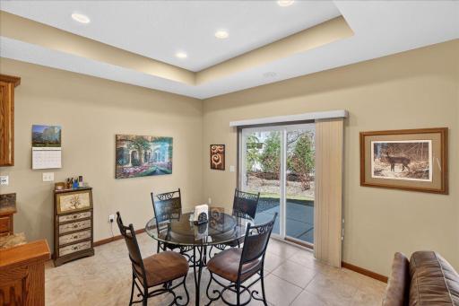 Bright and inviting dining area featuring tray ceilings, tile flooring, and a sliding glass door that opens to a private patio — perfect for indoor-outdoor entertaining.