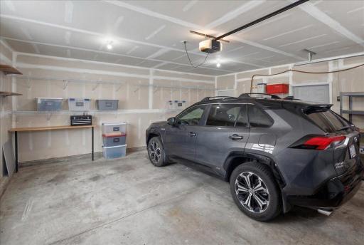 Spacious attached garage with room for vehicles, storage, and workspace.