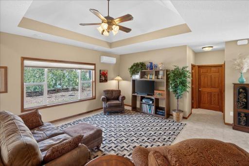 Bright and comfortable living room featuring a large picture window, tray ceiling detail, and plenty of space for seating and relaxation.