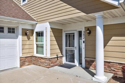 Step-free front entry with a covered porch, brick accents, and a secure storm door — offering easy, convenient access with no stairs.