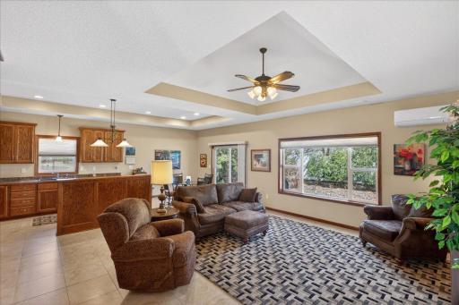 Spacious open-concept living room with tray ceiling, large windows, and seamless flow into the kitchen and dining area — perfect for everyday living and entertaining.