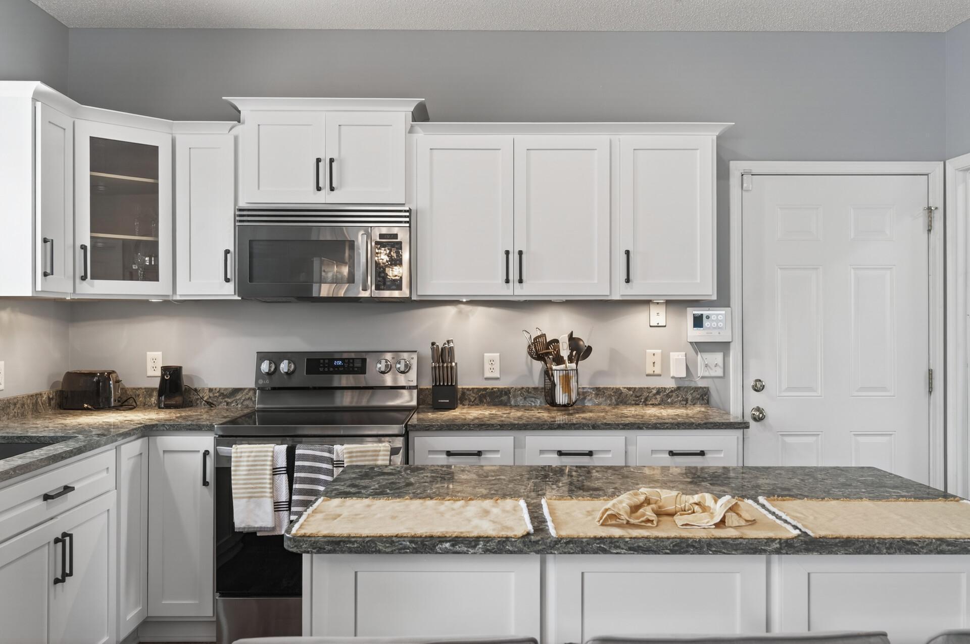 Well-designed kitchen layout featuring refaced cabinetry, ample countertop space, under-cabinet lighting, and fresh paint throughout.