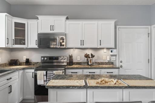 Well-designed kitchen layout featuring refaced cabinetry, ample countertop space, under-cabinet lighting, and fresh paint throughout.
