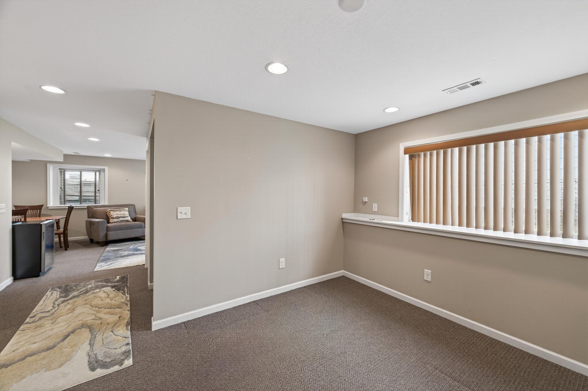 Spacious lower-level living area featuring plush carpeting and recessed LED lighting, offering flexible space for a family room, recreation area, or potential 4th bedroom with the addition of a wall and door.