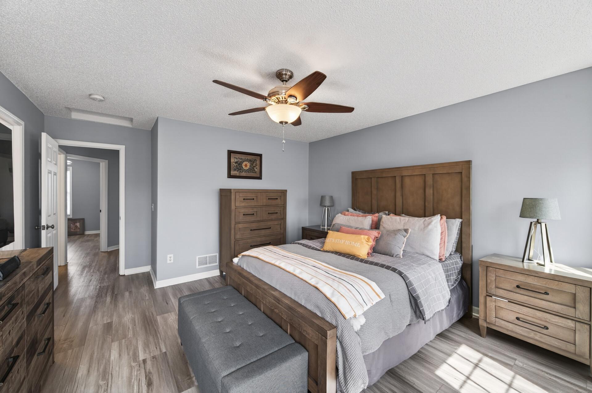 Primary bedroom showcasing new luxury vinyl plank (LVP) flooring, ceiling fan, and expansive layout with room for additional seating and furniture.
